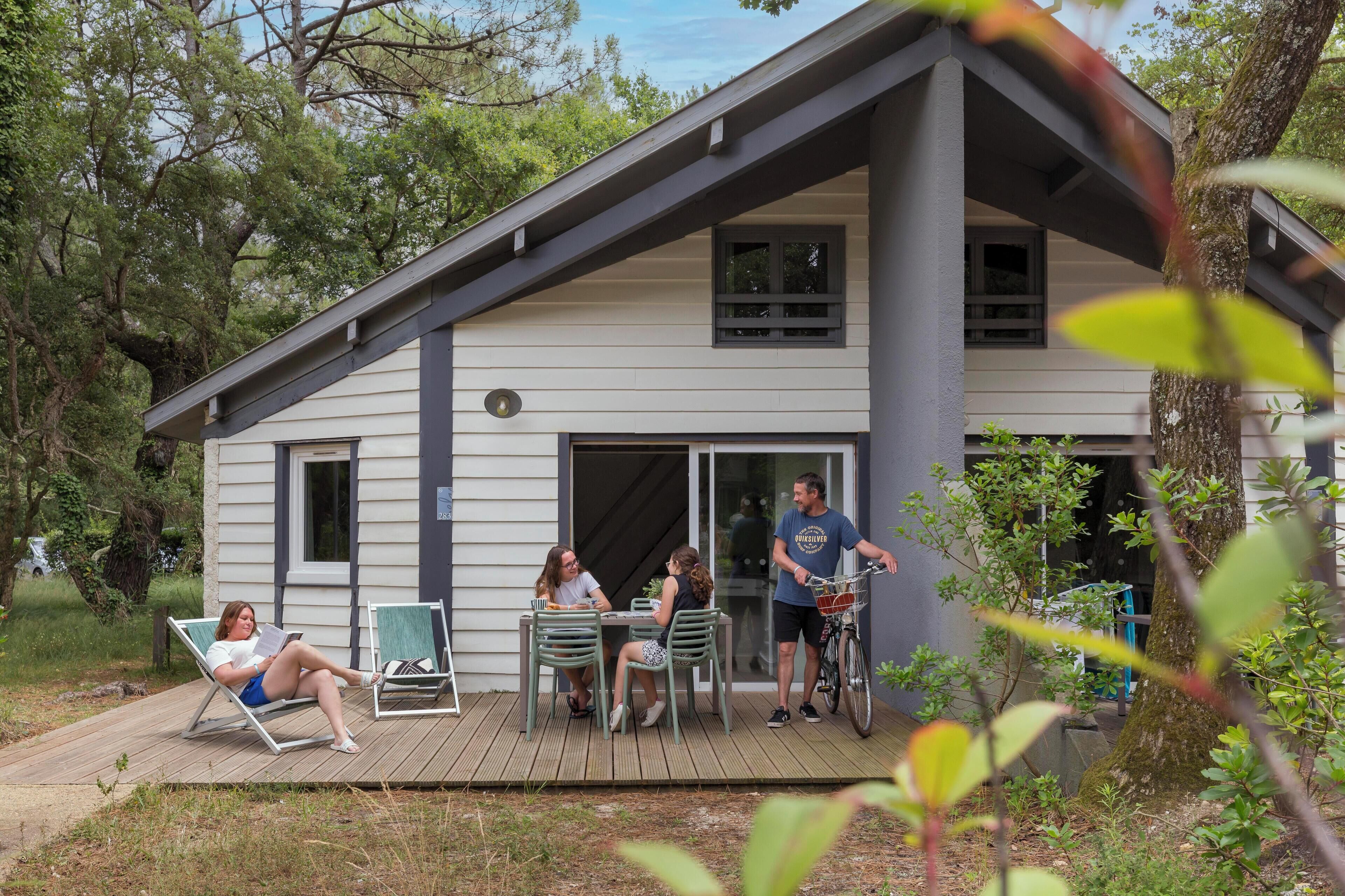 A modern house with a deck, outdoor seating, and a bicycle.