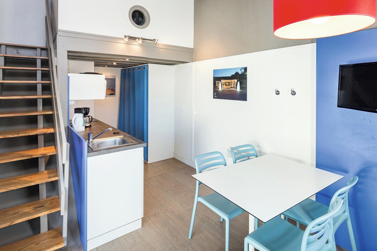 Een kleine keuken met een koffiezetapparaat, een wastafel en een blauw gordijn.