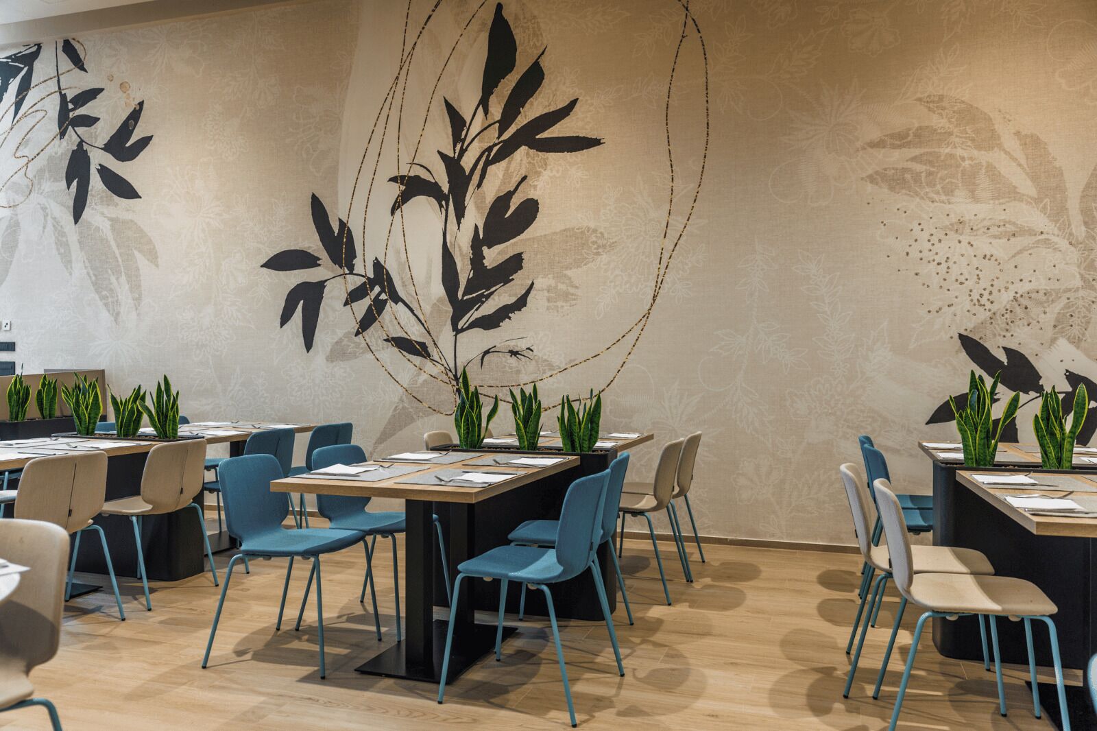 A modern conference room with a long table, blue chairs, and potted plants.