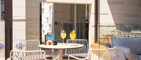 Un área de estar al aire libre con una mesa redonda, sillas y un libro titulado 'TAKE A MINUTE'.
