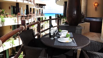 Un comedor con mobiliario de mimbre, un jacuzzi y vista al océano.