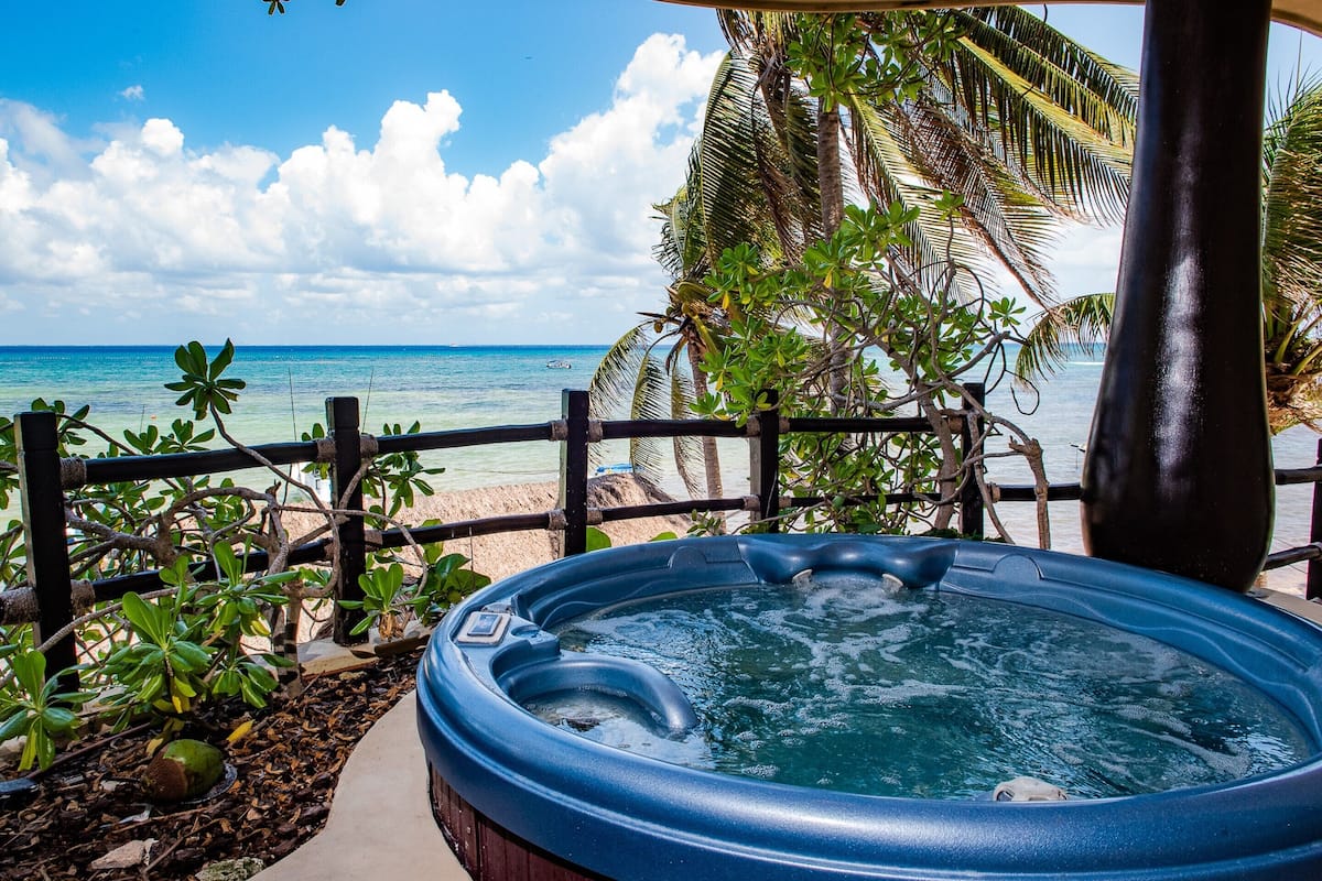 A hot tub with a view of the ocean and palm trees.