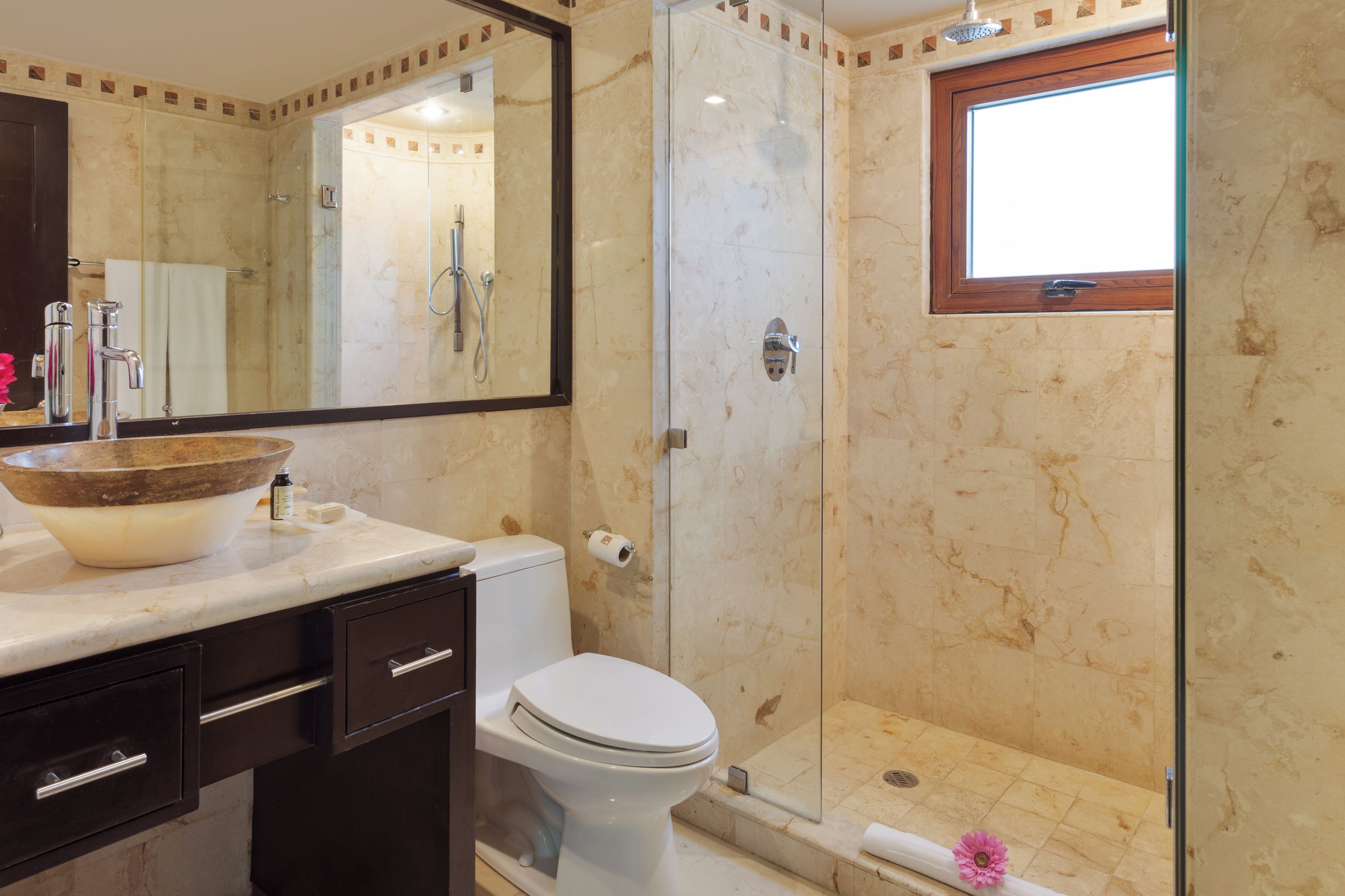 A bathroom with a marble sink, a toilet, and a glass-enclosed shower.