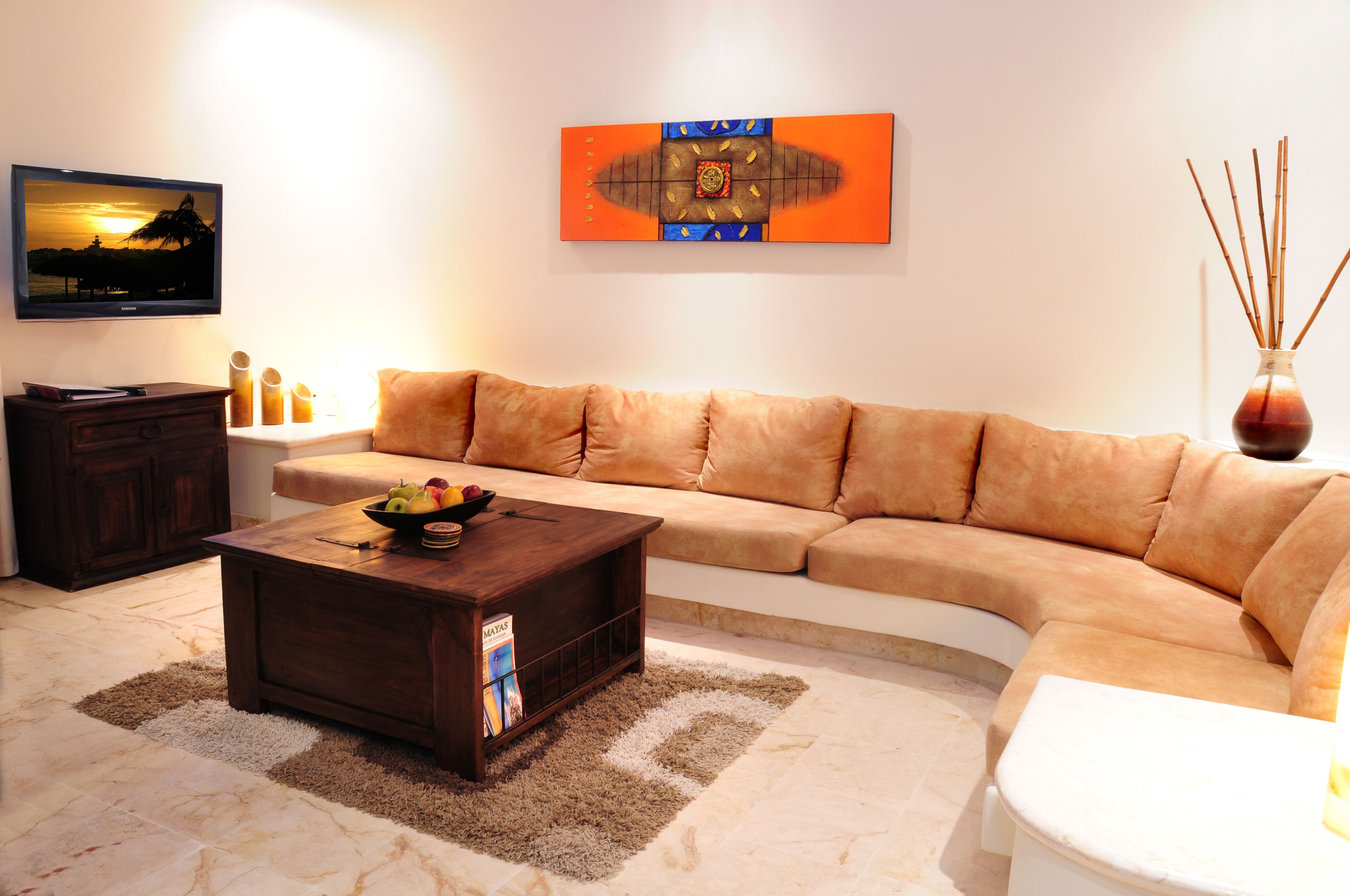 A living room with a sofa, coffee table, TV, and artwork on the wall.
