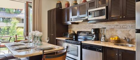 Una cocina moderna con armarios de madera oscura, electrodomésticos de acero inoxidable y un amplio ventanal con vistas a un jardín.