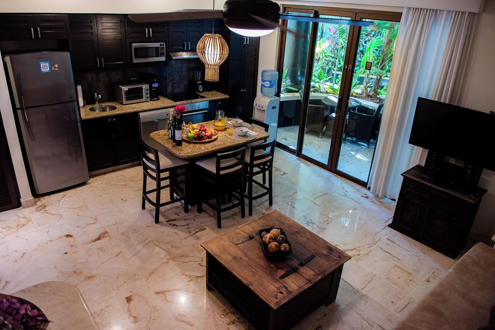 A modern kitchen with dark cabinets, a microwave, and a dining area with a wooden table and chairs.