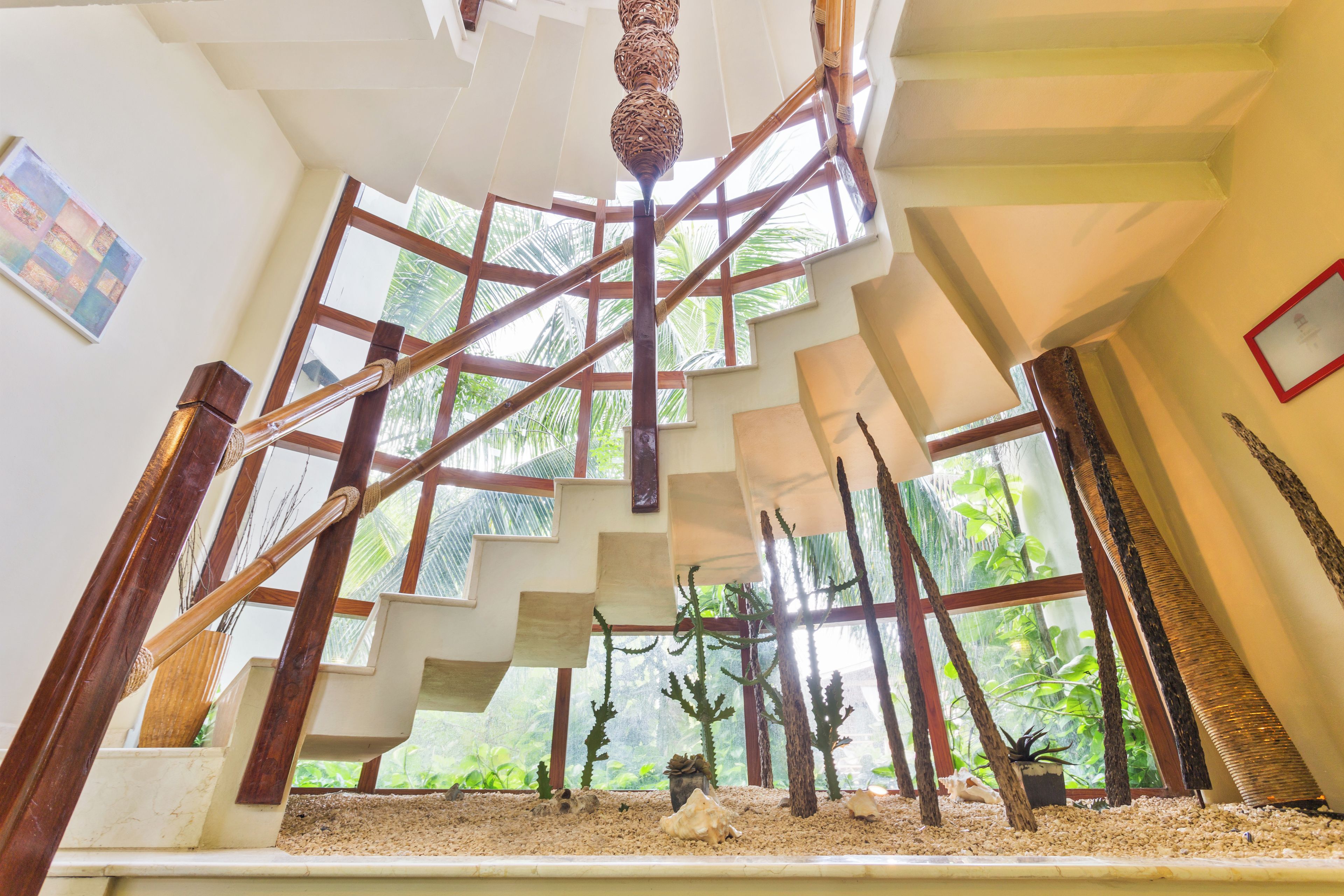 A spiral staircase with a view of tropical plants outside.