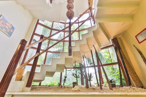 Un escalier en colimaçon offrant une vue sur la végétation tropicale à l’extérieur.
