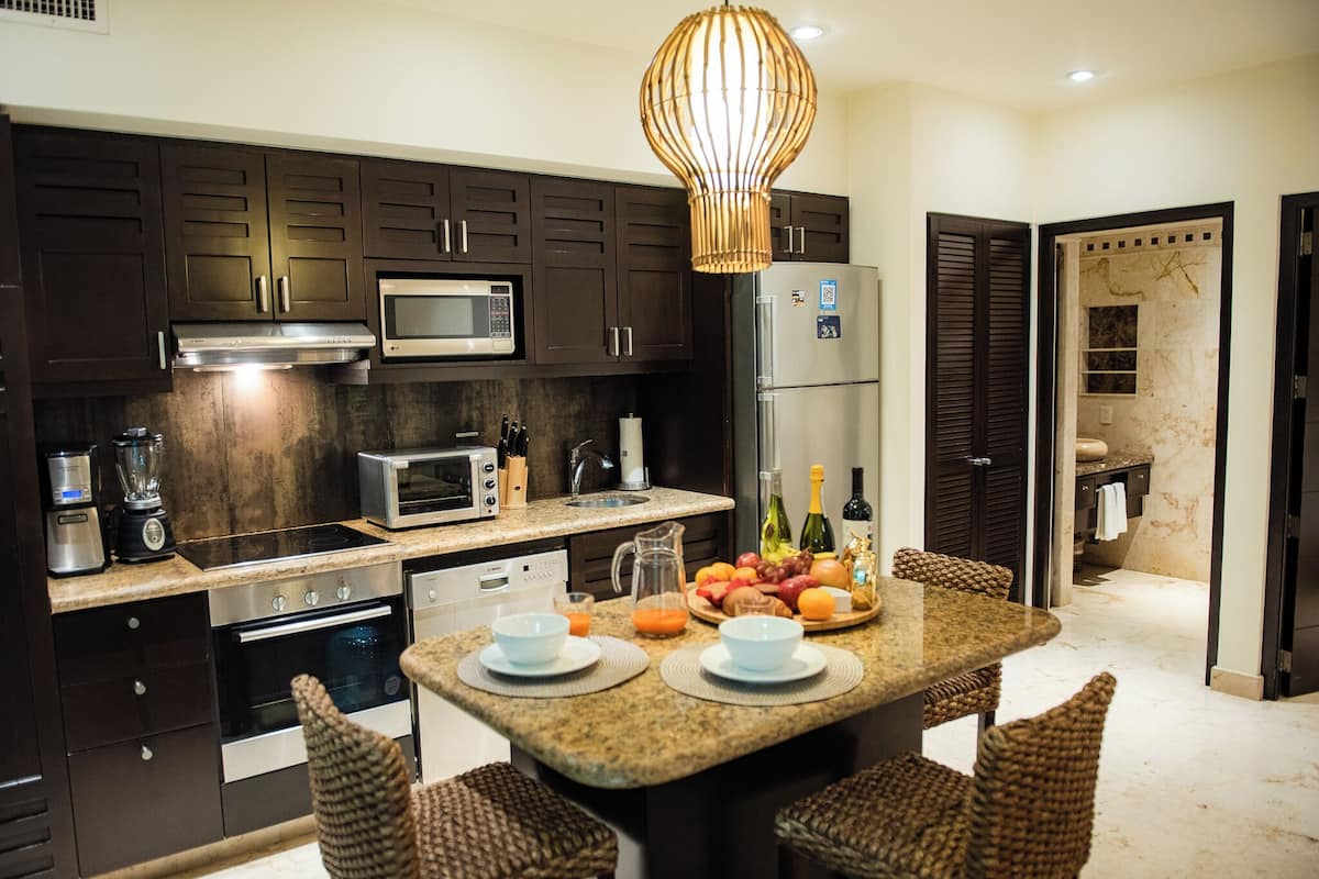 A modern kitchen with dark wood cabinets, stainless steel appliances, a granite countertop, and a central island with seating.