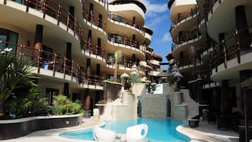 A multi-story hotel with a central pool, balconies, and tropical landscaping.