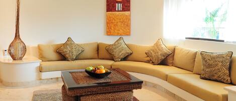 A living room with a beige sofa, a woven coffee table, and a wall-mounted painting.