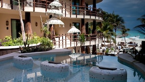 Ein Pool mit Mosaikfliesen, Palmen und Blick auf den Strand.