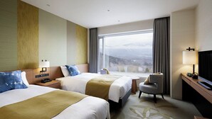 A hotel room with two beds, a desk, a chair, a TV, and a large window with a mountain view. - Shizukuishi Prince Hotel (Shizukuishi)