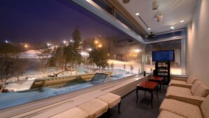 A modern interior with a seating area, a television, and a view of a snowy landscape outside. - Shizukuishi Prince Hotel (Shizukuishi)