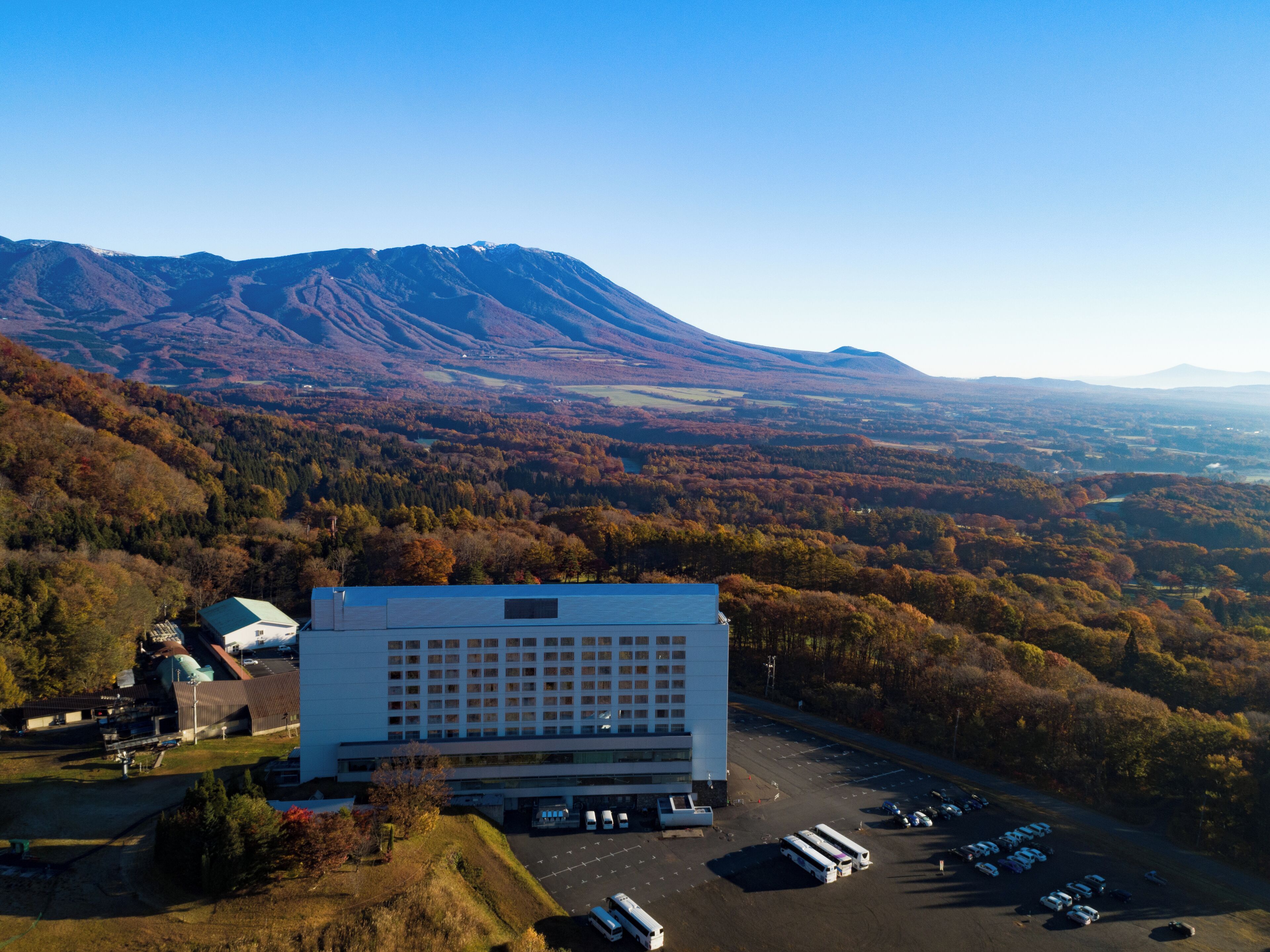 Un hotel moderno con aparcamiento y montañas al fondo.