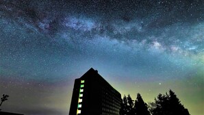 Un edificio con esquina destacada y numerosas ventanas, sobre un cielo estrellado.