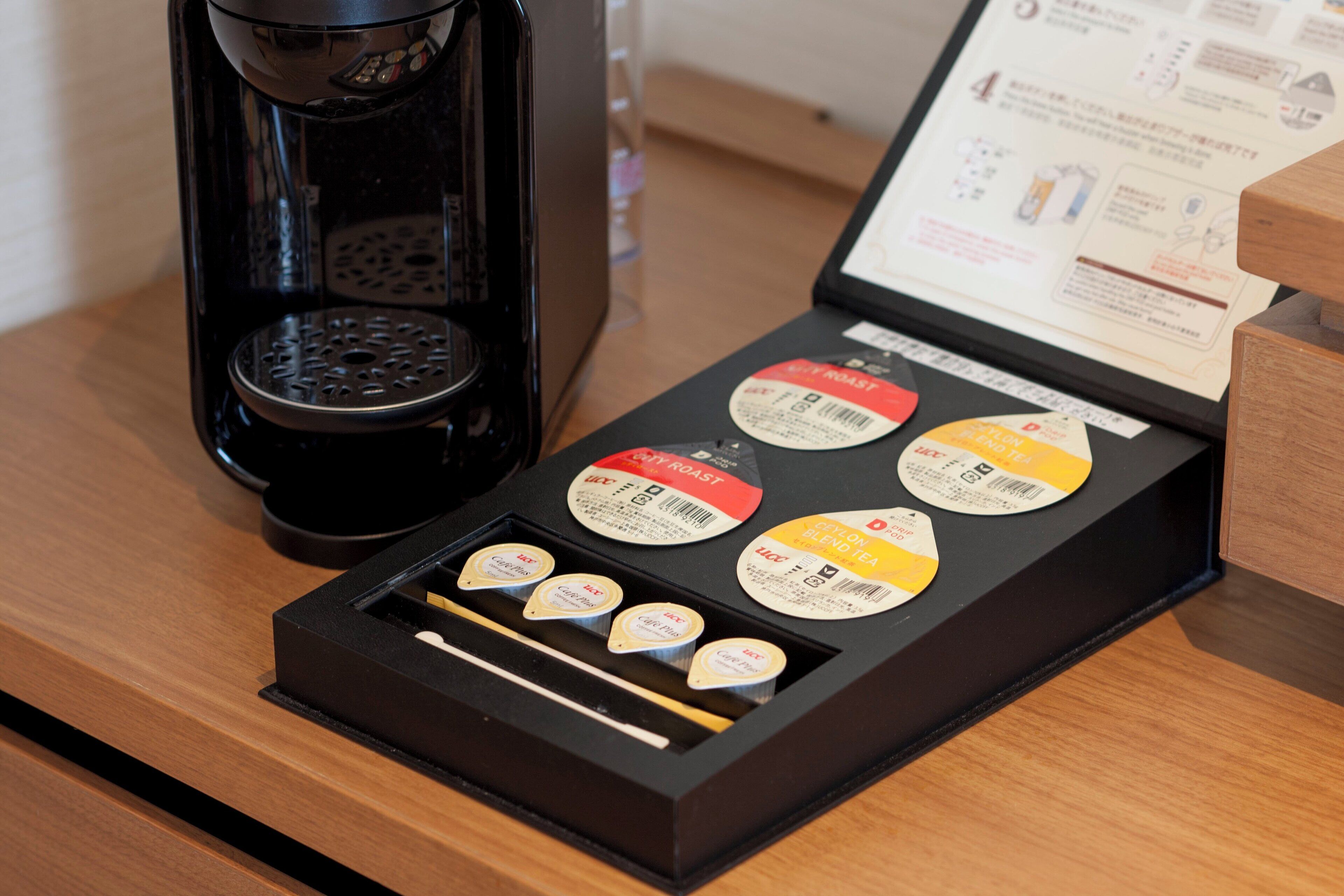 Una cafetera y una caja de cápsulas de café con etiquetas sobre una superficie de madera.
