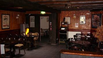 A restaurant interior with wooden walls, tables, and chairs. There are framed pictures on the walls and a menu board.