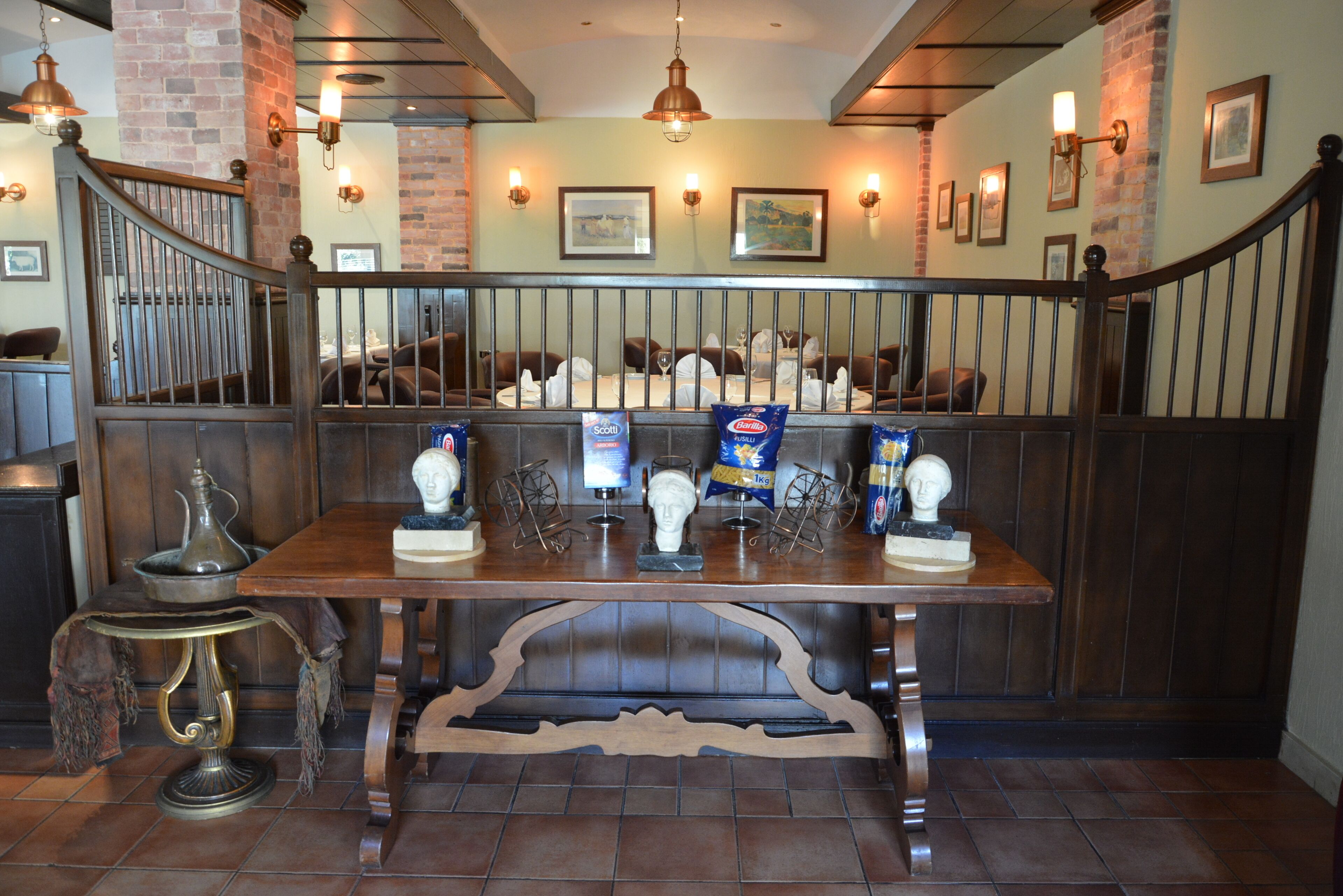 Uma área de refeições com mesa de madeira, cadeiras e um guarda-corpo decorativo.