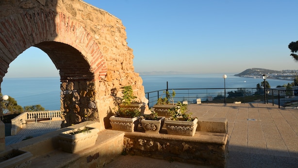 An ancient stone archway overlooking a coastal view with potted plants and a paved area. - Golden Carthage Residence (La Marsa)