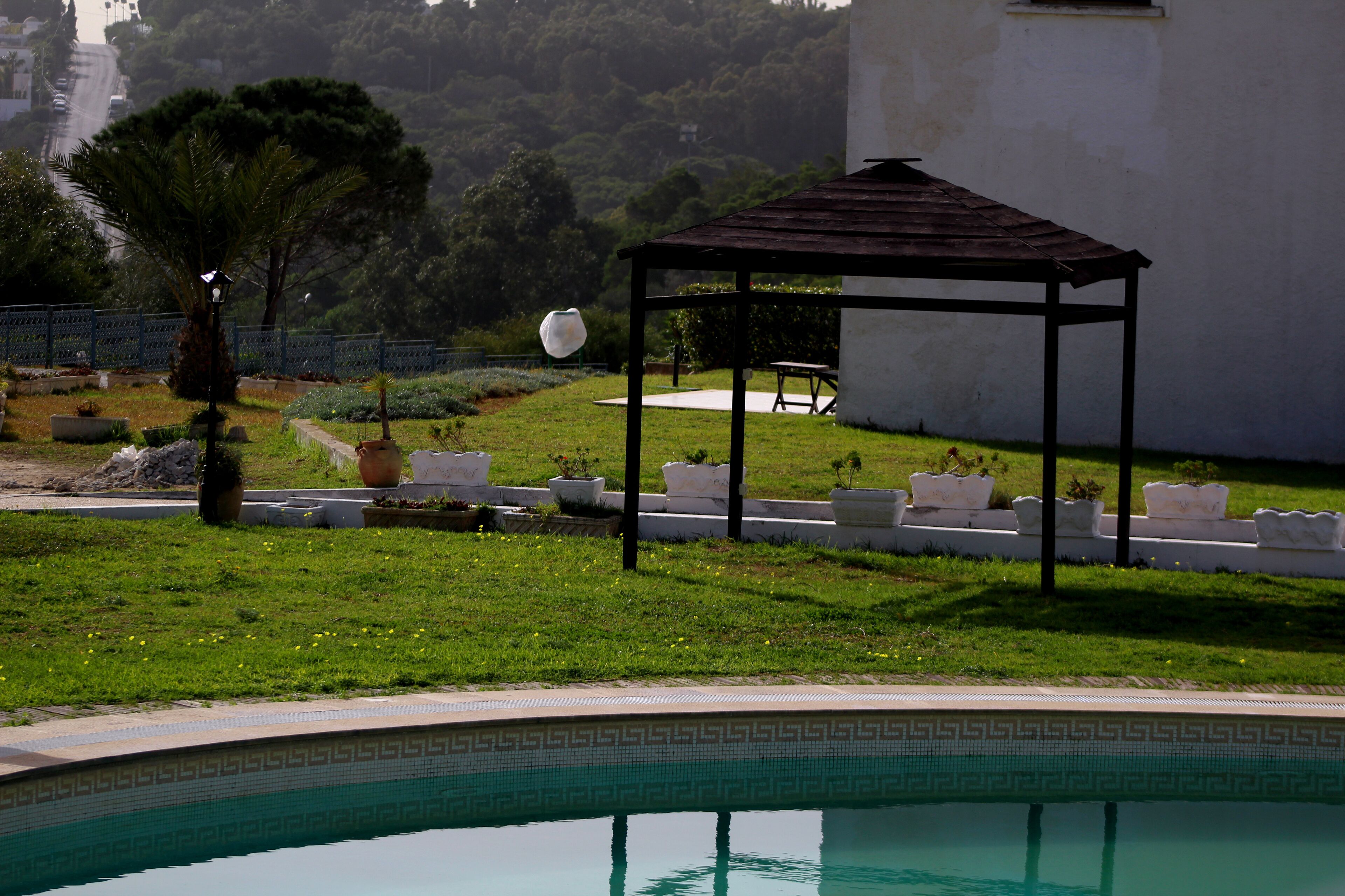 A pool area with a gazebo, seating, and a landscaped garden.