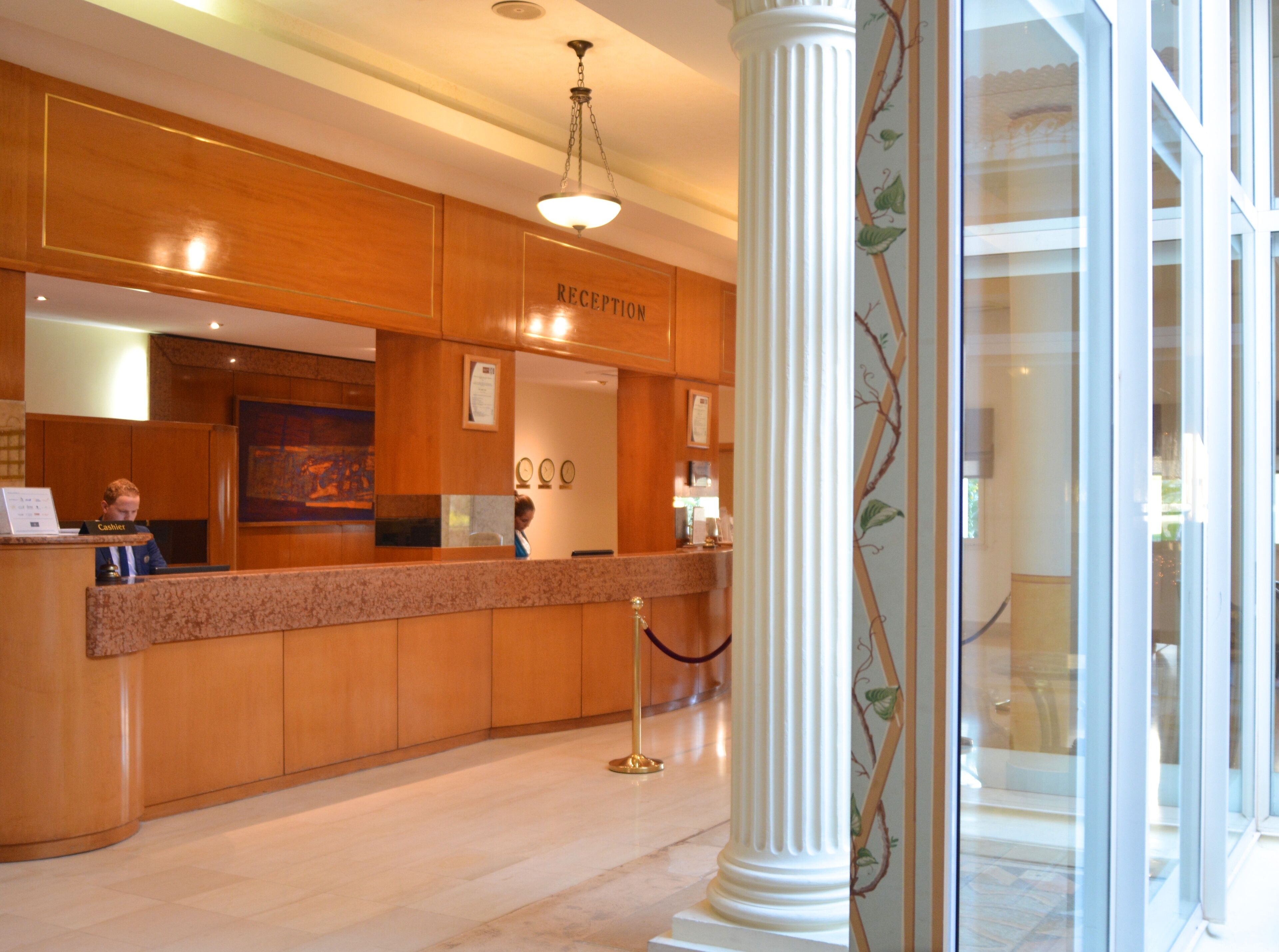 A reception area with a wooden reception desk, a cash register, and a framed certificate on the wall.