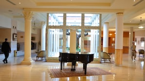 A grand lobby with a grand piano, marble flooring, and classical columns. - Golden Carthage Residence (La Marsa)