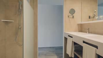 Un baño moderno con ducha, lavamanos y espejo.