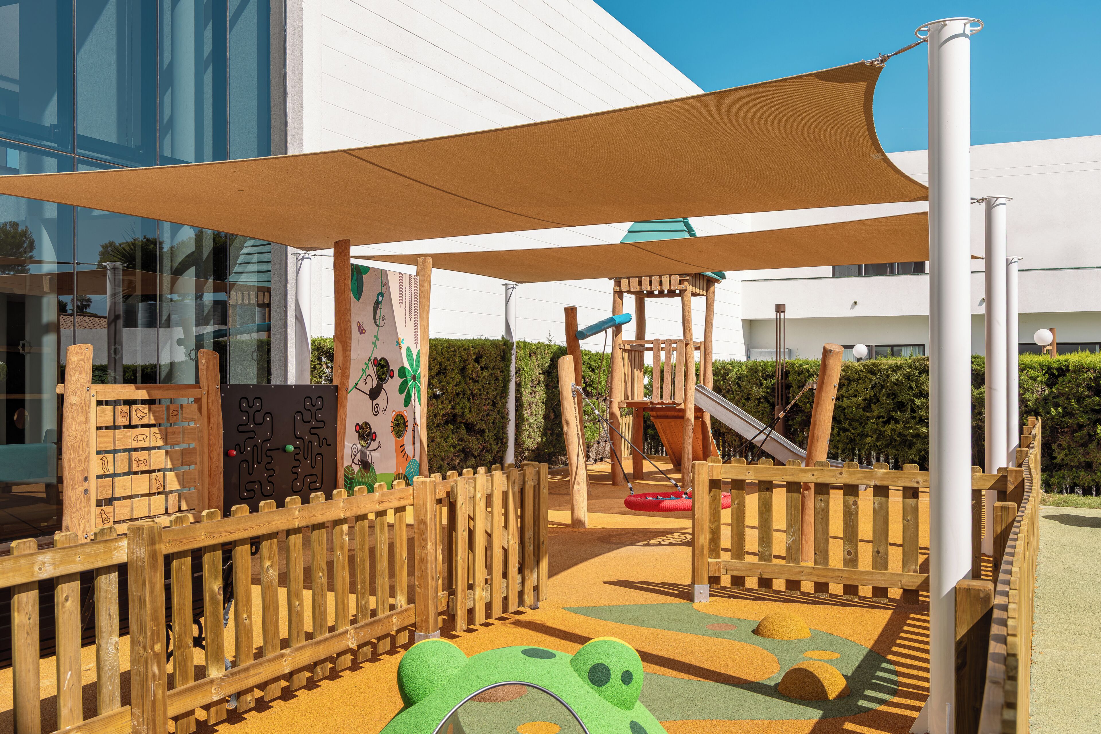Zona de juegos infantiles con tobogán, estructuras para escalar y un arenero.