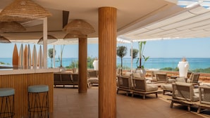 Een strandlounge met rieten meubilair, een bar en uitzicht op de oceaan.
