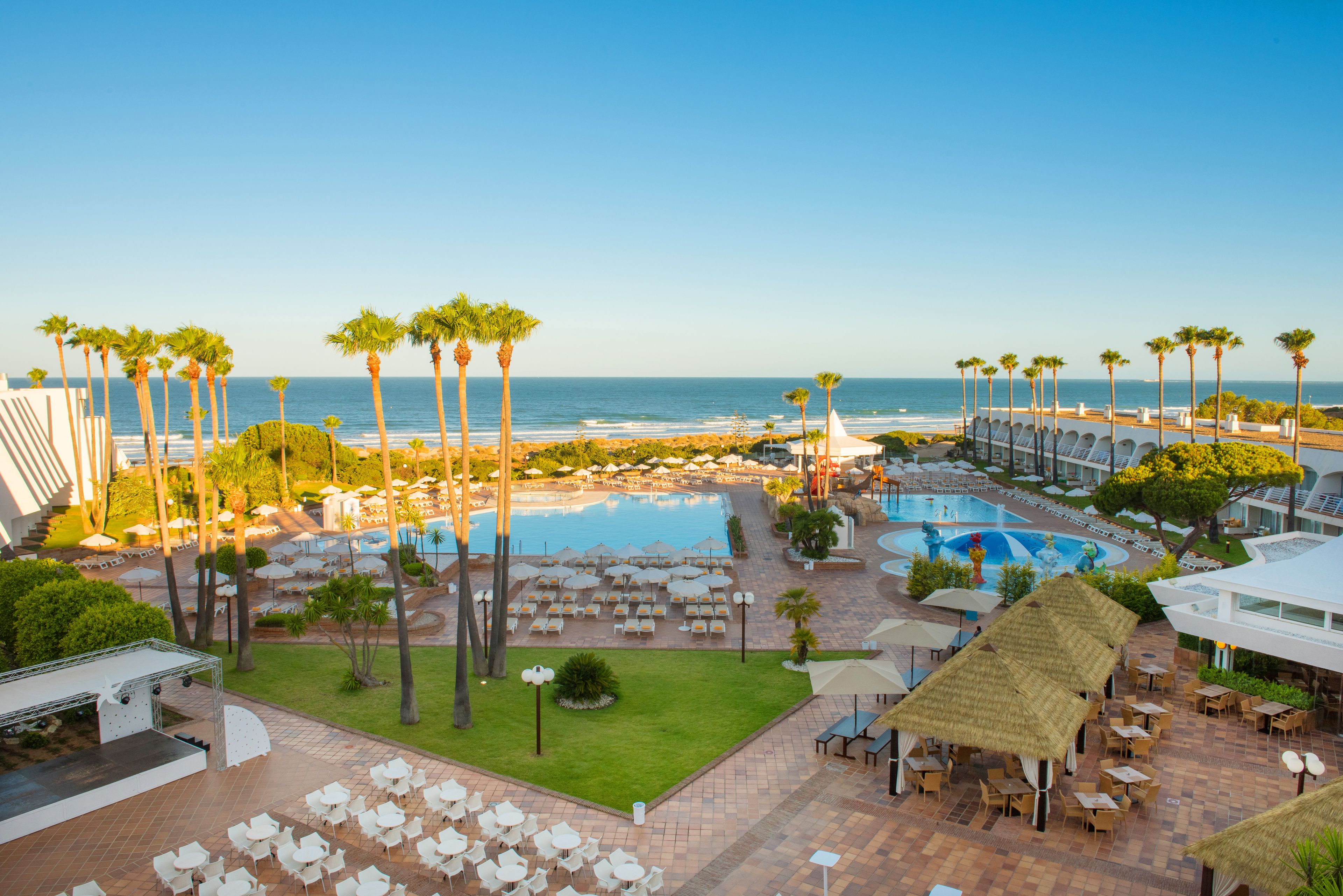 A resort with multiple pools, outdoor seating areas, and a view of the ocean.