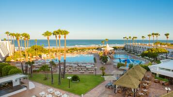 A resort with multiple pools, outdoor seating areas, and a view of the ocean.