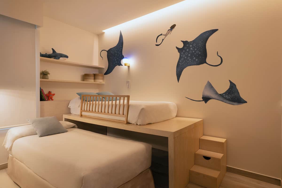 Een kinderkamer met een stapelbed, een ledikant en muurstickers van zeedieren.