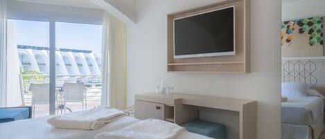 Habitación de hotel con dos camas, un escritorio, una televisión y vistas al exterior.