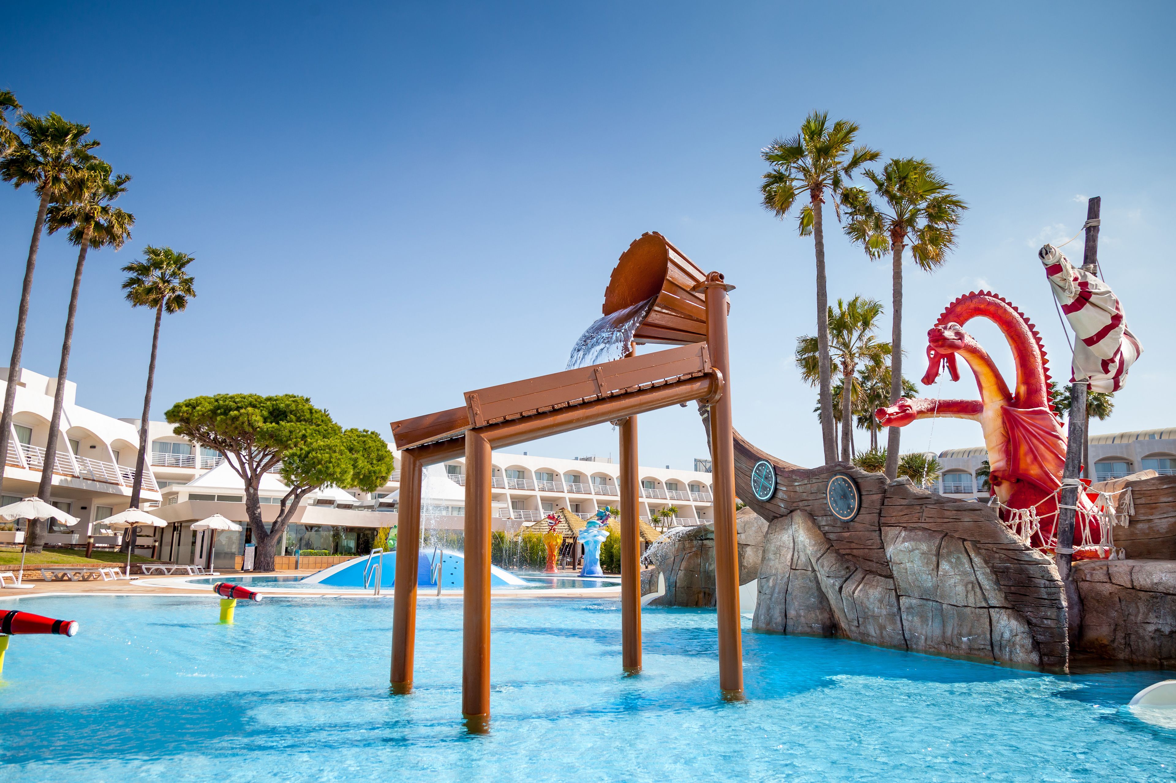 Ein Wasserpark mit einem großen Pool, einer Holzkonstruktion und einer Drachenstatue.