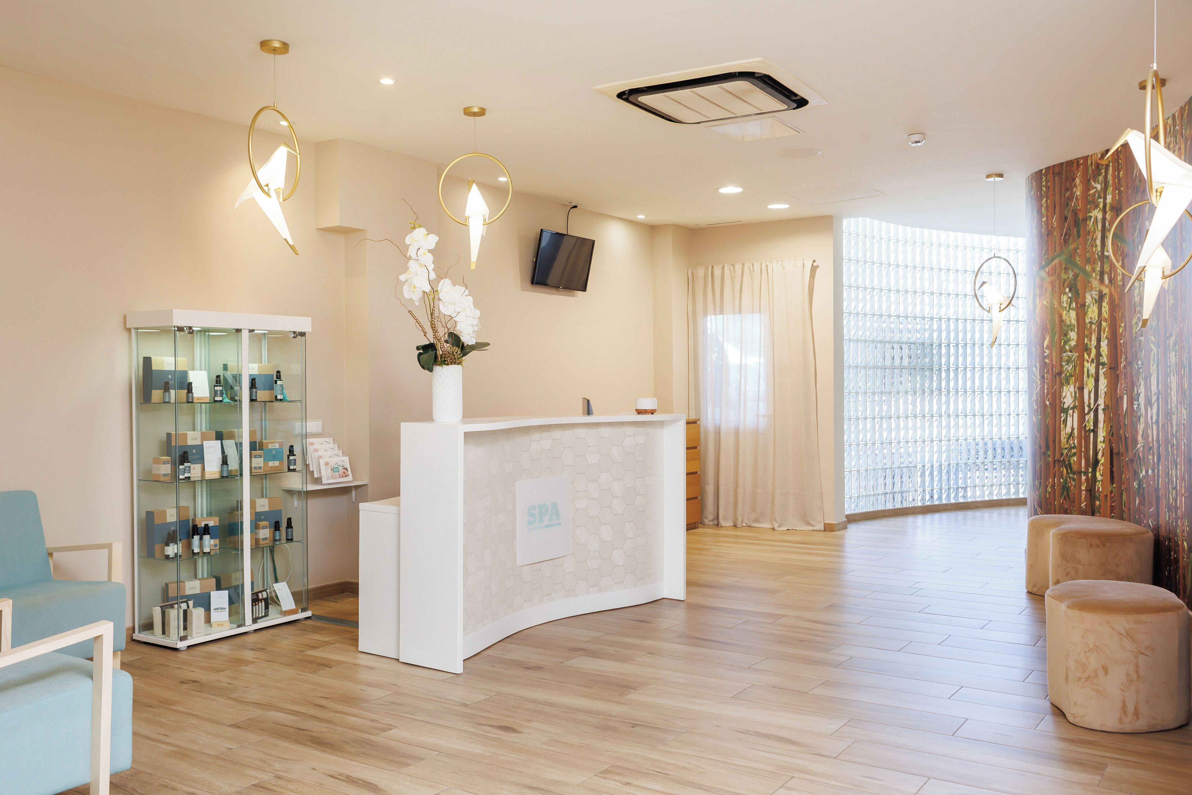 A reception area with a white counter, a glass display case, a blue chair, and a wooden floor.