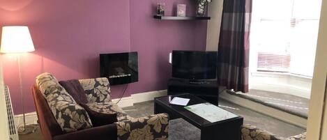 A living room with a sofa, a coffee table, a TV, and a lamp.