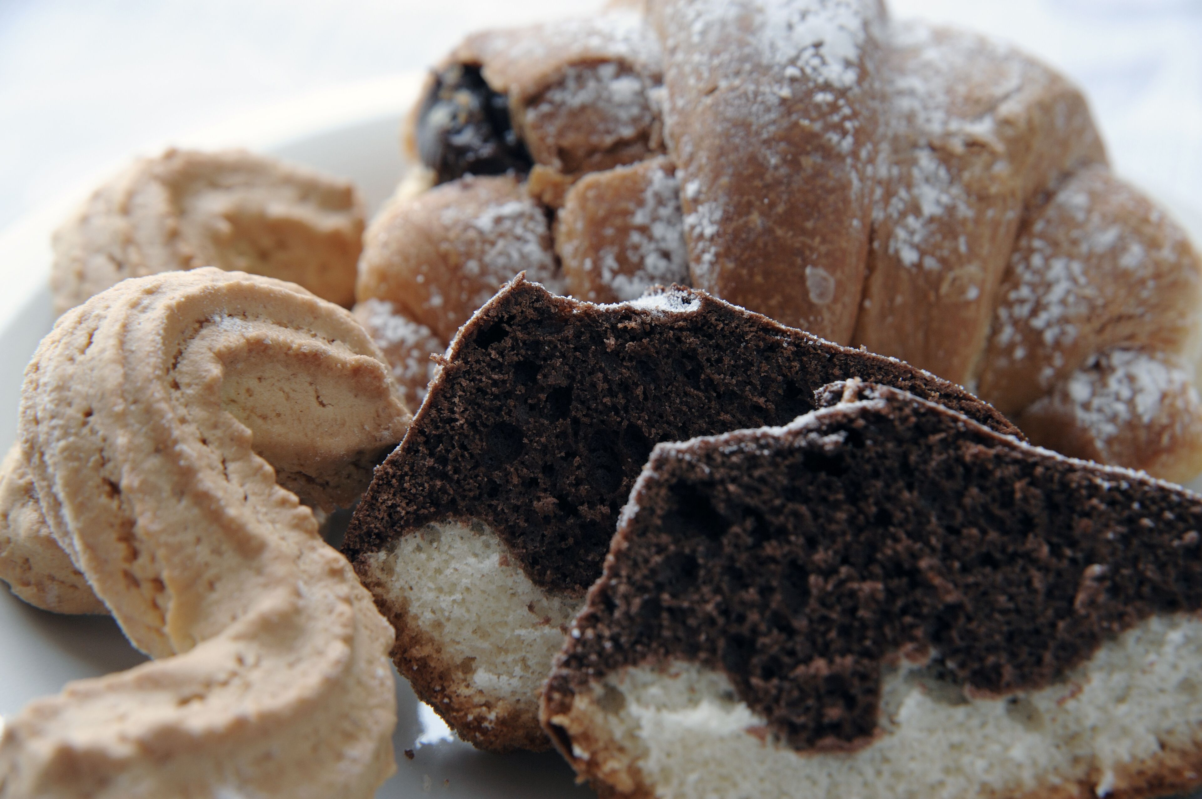 A plate with various pastries including a chocolate cake slice and a rolled pastry.