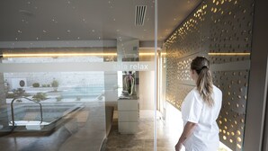 Un interior moderno con un separador de vidrio, un lavamanos y vistas a un área de piscina exterior.