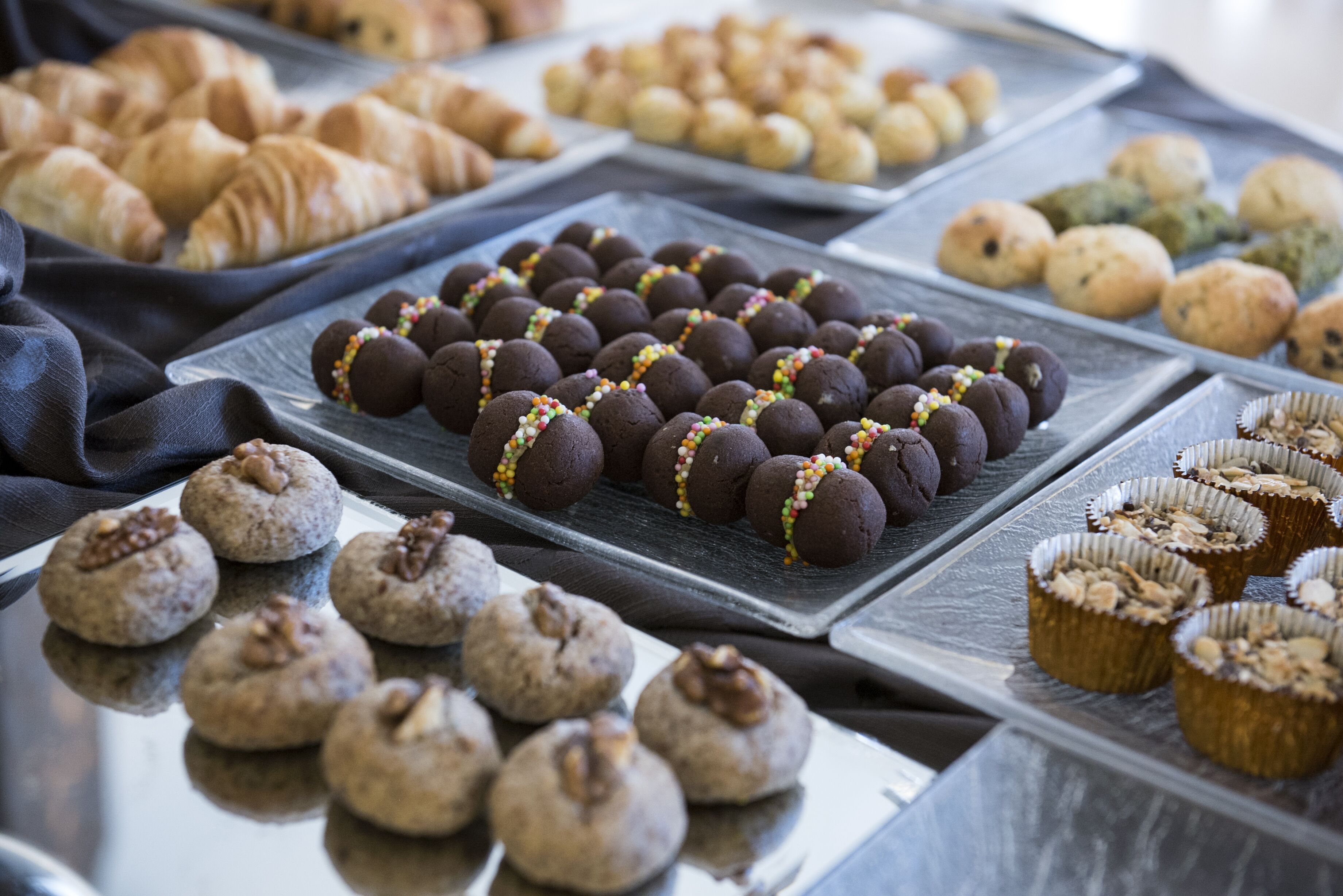 A variety of baked goods including cookies, pastries, and muffins arranged on trays.