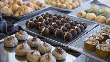 A variety of baked goods including cookies, pastries, and muffins arranged on trays.