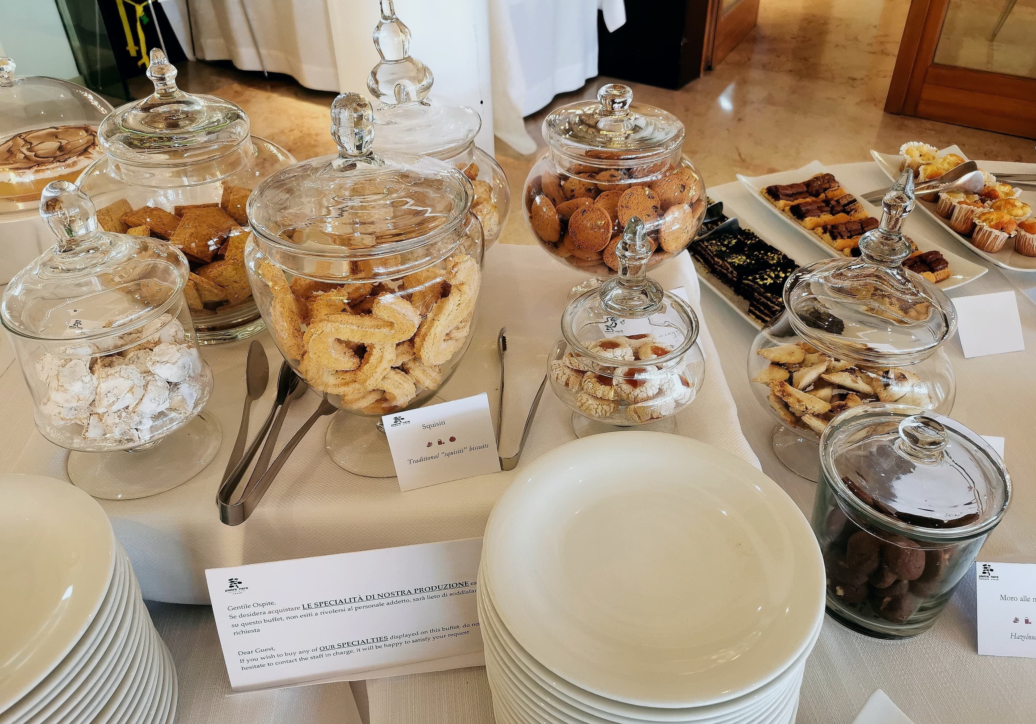 Ein reichhaltiges Buffet mit verschiedenen Speisen in Glasbehältern, ergänzt durch Teller und Besteck.