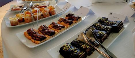 A buffet table with various desserts and pastries.