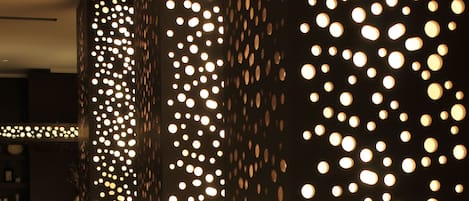 A corridor with walls adorned with circular light fixtures, creating a pattern of illuminated dots.