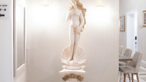 A statue in a hallway with a modern interior design, including a dining area in the background. - Hotel Bijou Roof Terrace (Florence)