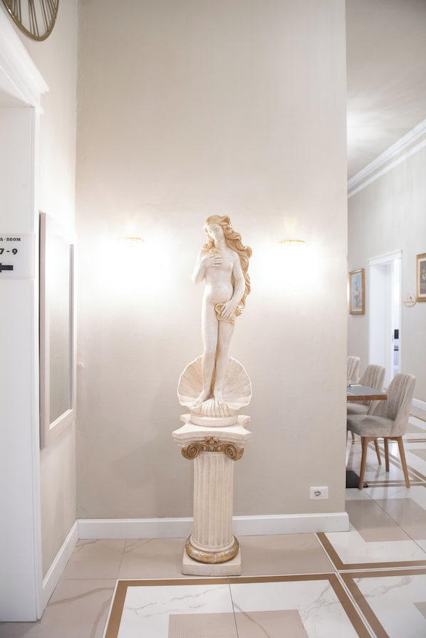 A statue in a hallway with a modern interior design, including a dining area in the background. - Hotel Bijou Roof Terrace (Florence)
