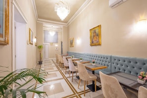 A hotel lobby with a long reception desk, a blue cushioned bench, and a chandelier. - Hotel Bijou Roof Terrace (Florence)