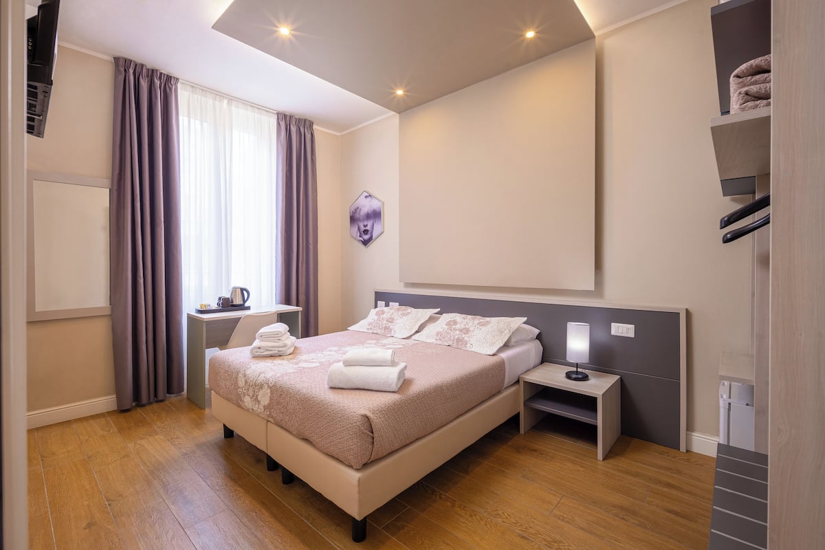 A modern bedroom with a bed, bedside tables, a desk, and a wardrobe.