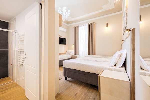 A modern hotel room with a large bed, a bedside table, a TV, and a chandelier. - Hotel Bijou Roof Terrace (Florence)