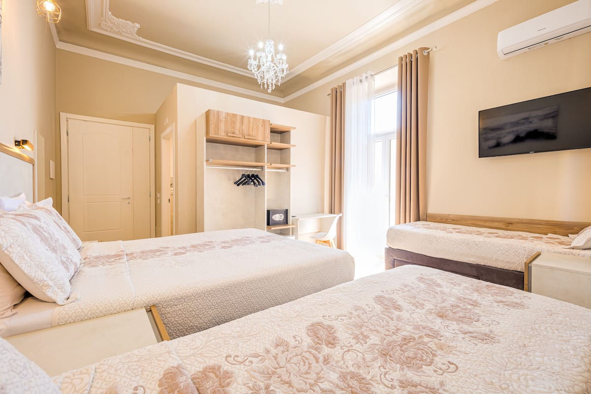 A hotel room with two beds, a wardrobe, a desk, and a television.